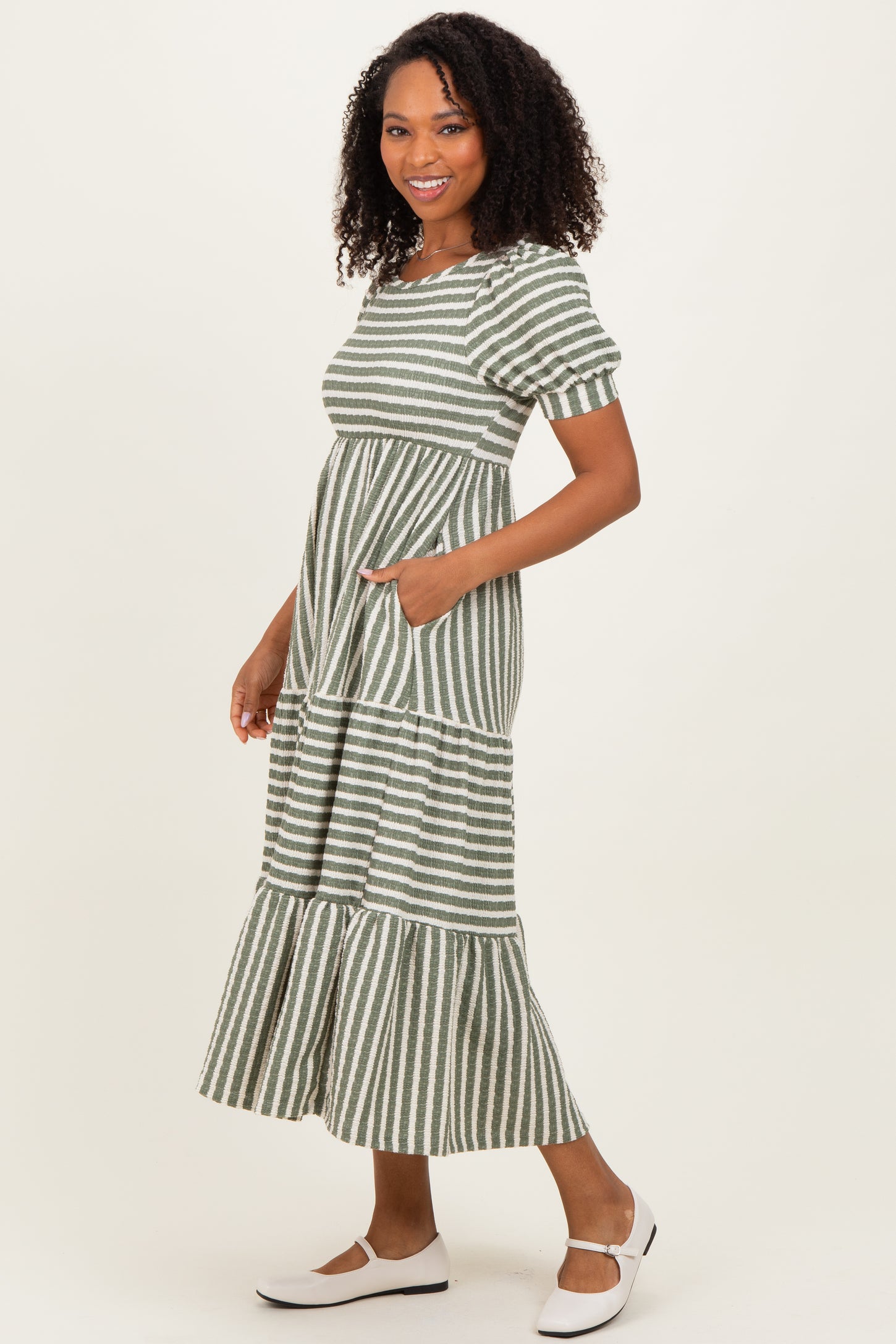 woman wearing a green and white striped maxi dress with short puff sleeves and pockets