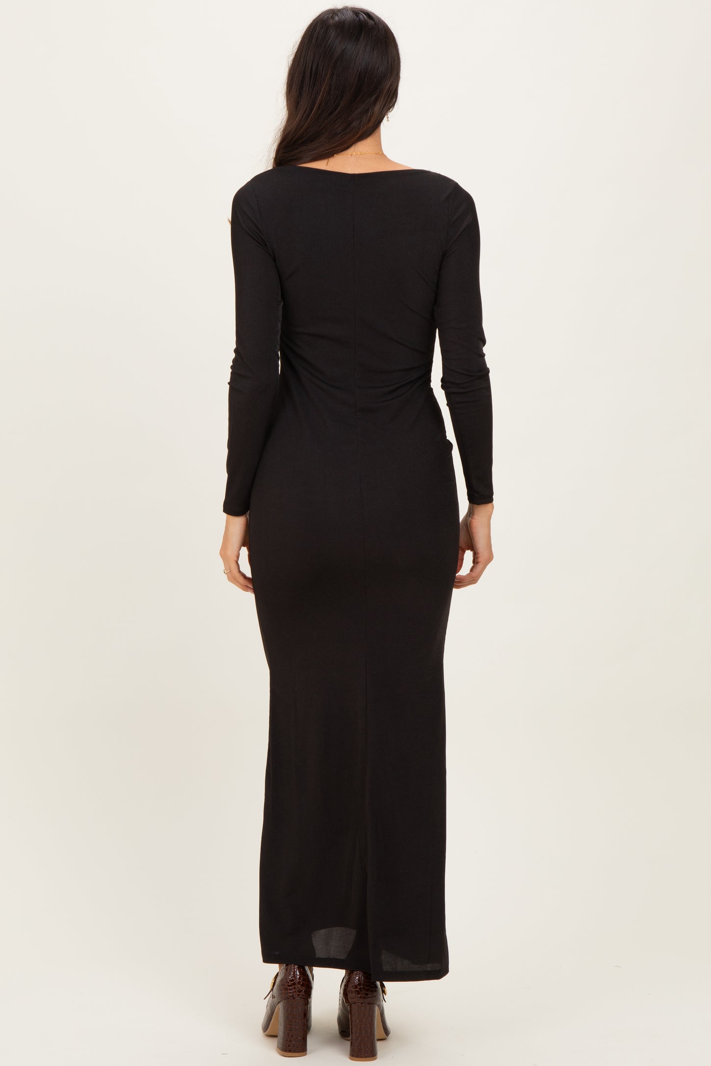 woman wearing a black long sleeve maxi dress, showing the back view with a fitted silhouette and a floor-length hem