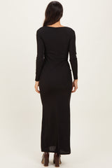 woman wearing a black long sleeve maxi dress, showing the back view with a fitted silhouette and a floor-length hem