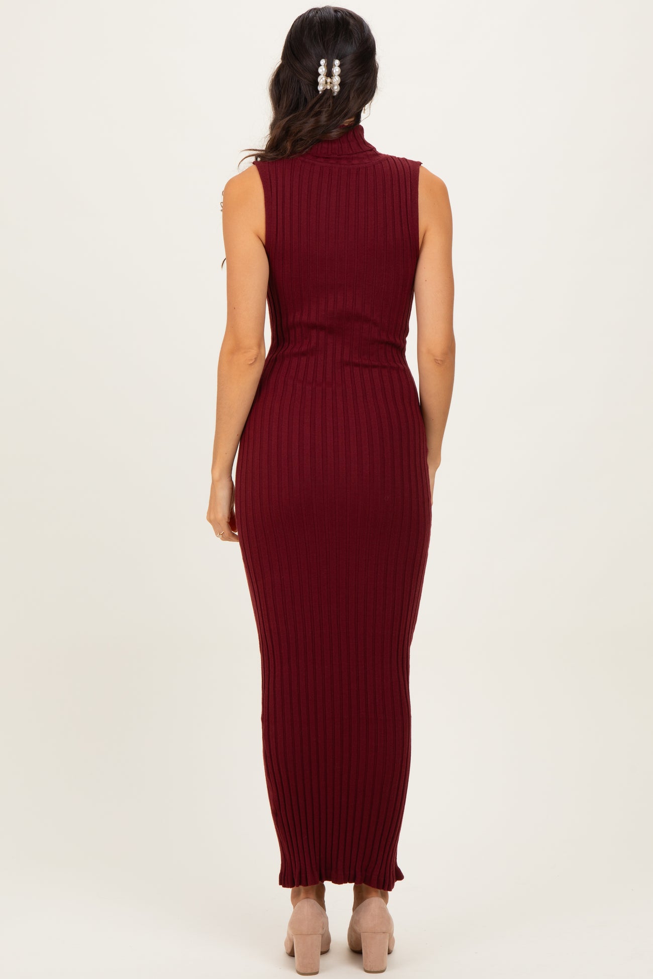 woman wearing a burgundy sleeveless ribbed maxi dress with a high neck and fitted style from the back