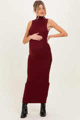 woman wearing a burgundy ribbed maternity dress, showing off her baby bump, styled with black ankle boots