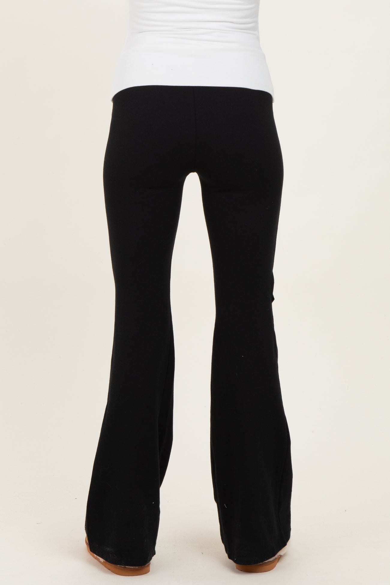 woman wearing black maternity flared pants, back view, fitted through the hips and flaring out at the hem