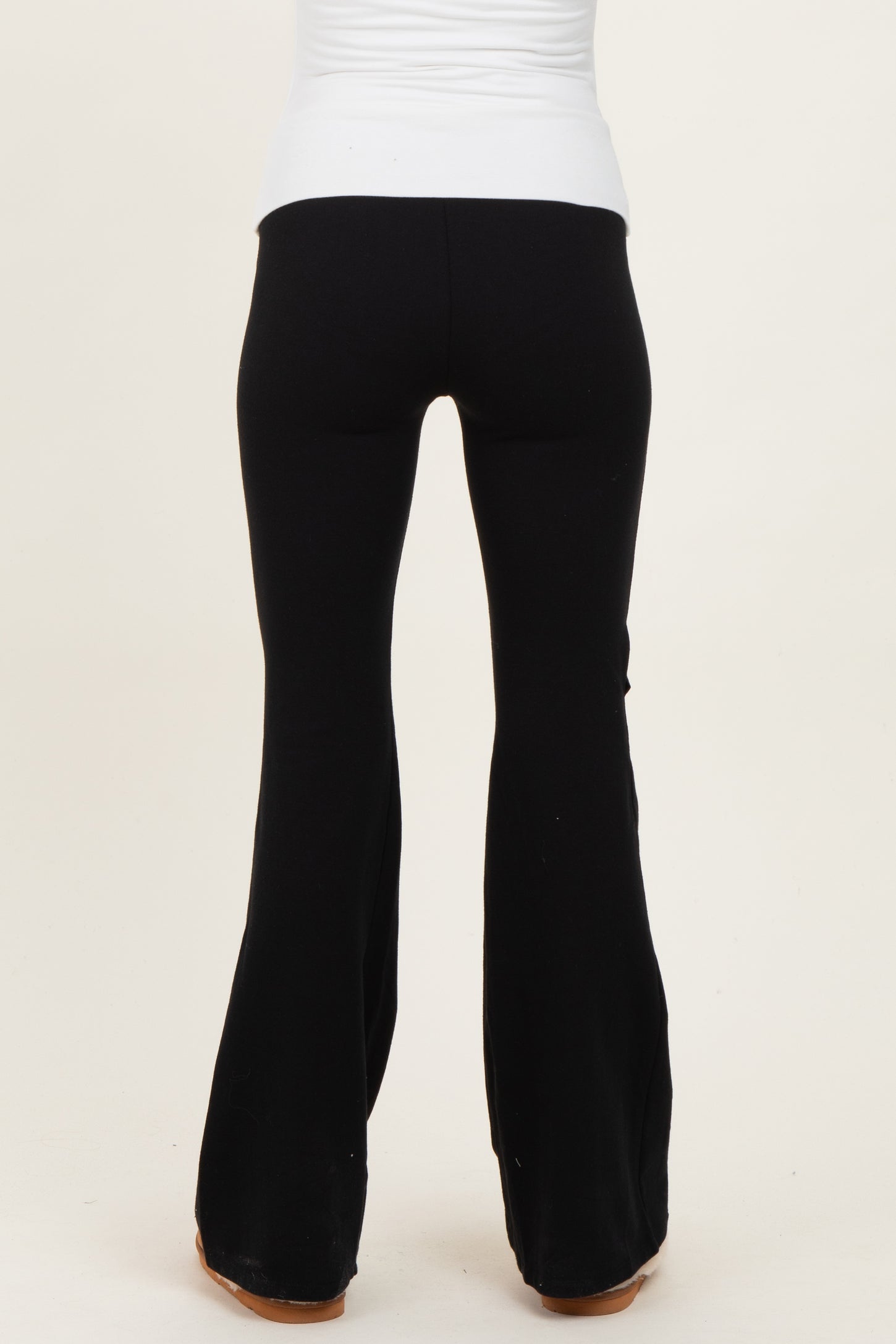 woman wearing black maternity flared pants, back view, fitted through the hips and flaring out at the hem