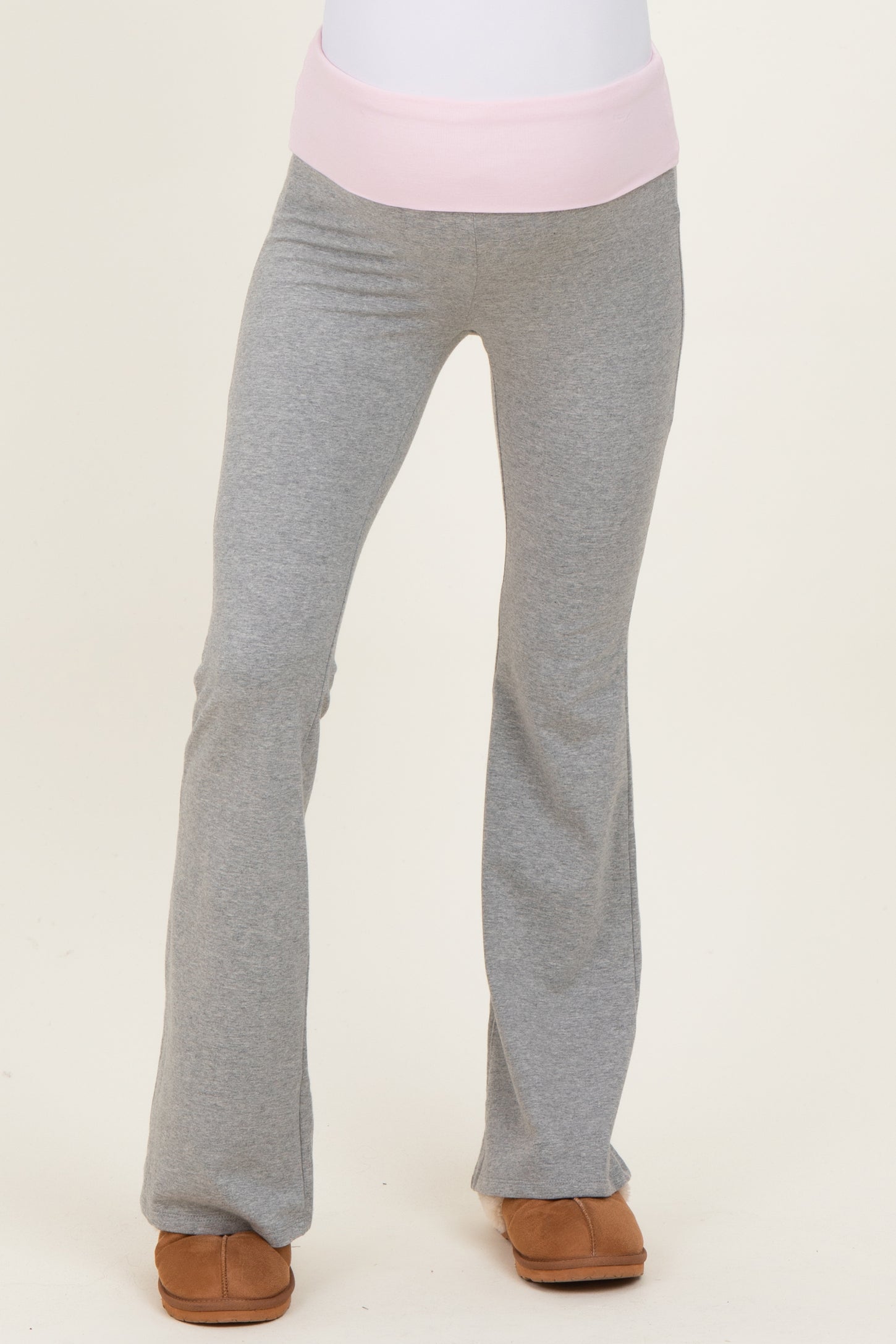 maternity wear gray flared pants with a pink waistband, model is wearing them standing upright