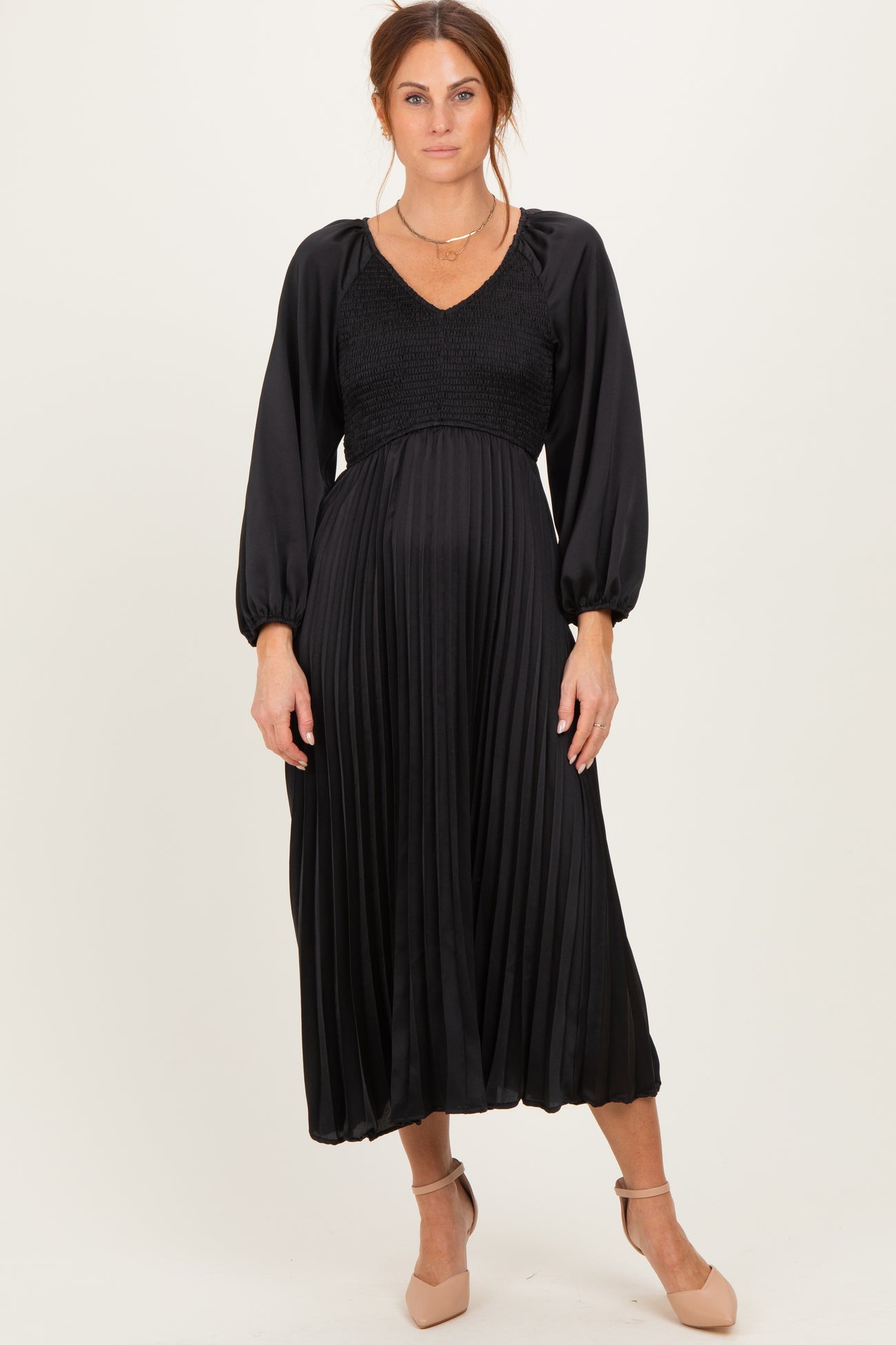 woman wearing a black pleated midi dress with smocked bodice and long sleeves