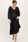 woman wearing a black pleated midi dress with a smocked bodice and long puff sleeves