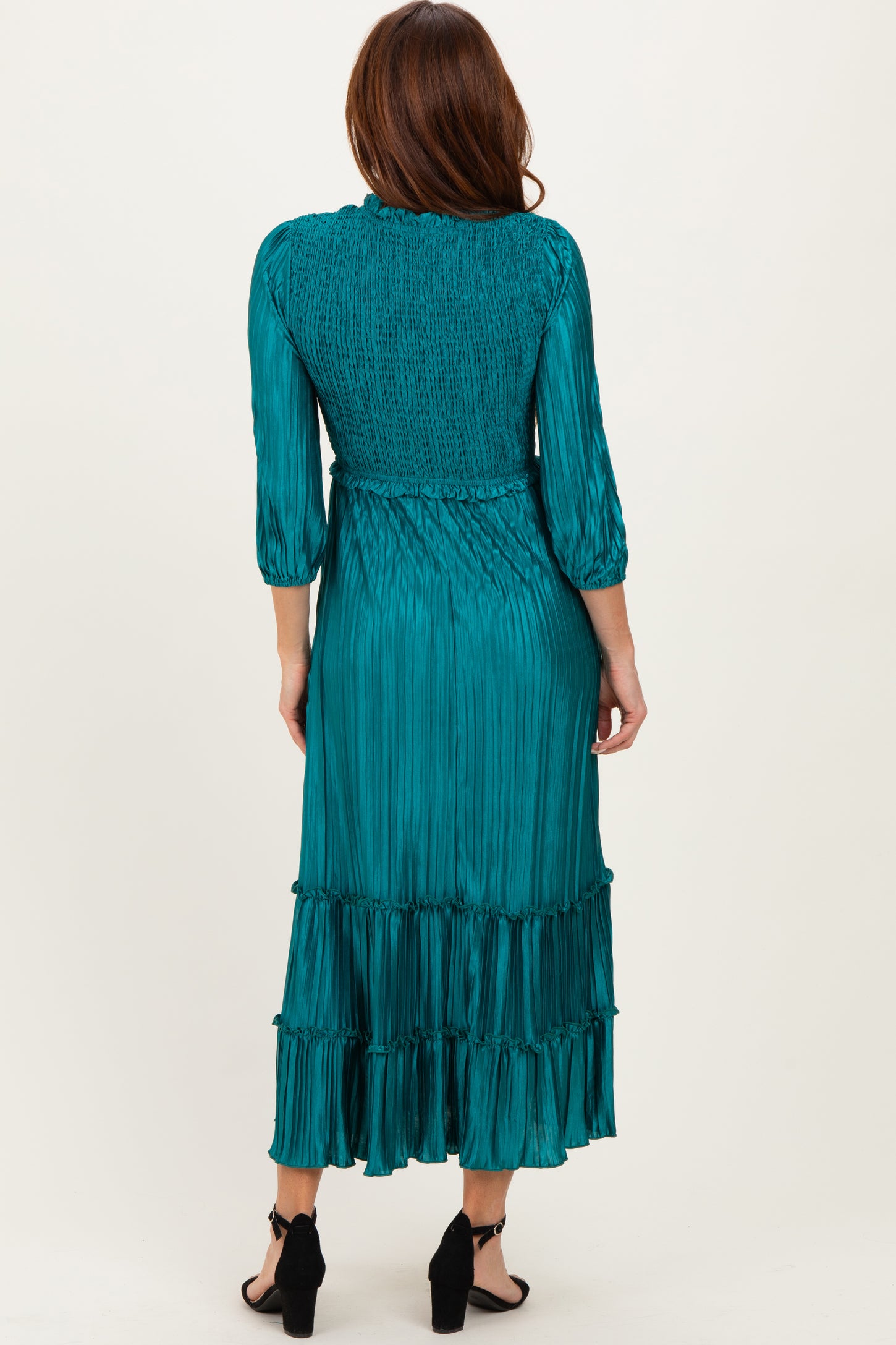 woman wearing a teal pleated long sleeve dress with a smocked bodice and tiered skirt