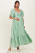 woman wearing a mint green maternity dress with puff sleeves and a tiered skirt, showing her baby bump