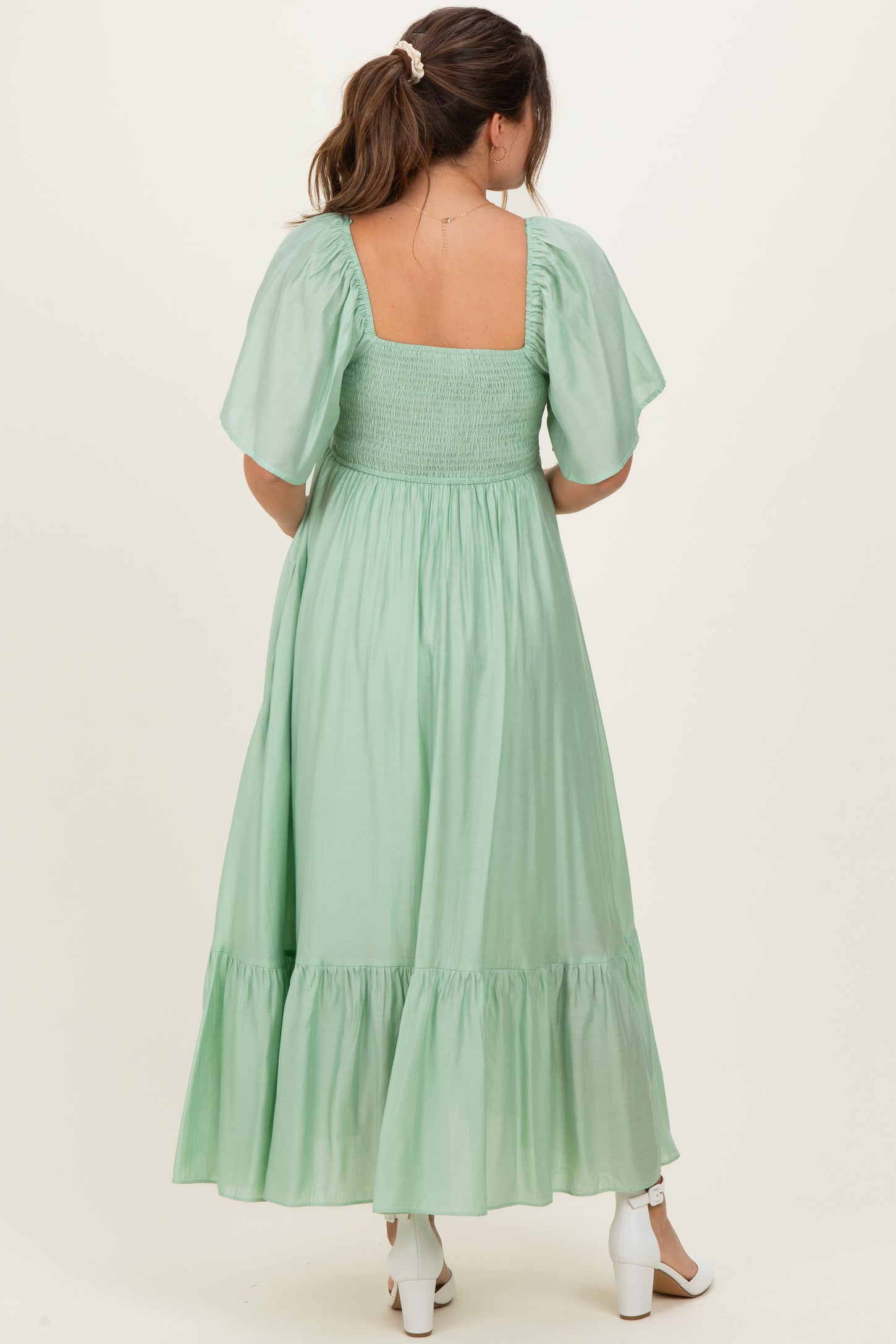 woman wearing a mint green maternity maxi dress with puff sleeves and smocked bodice, showing the back view