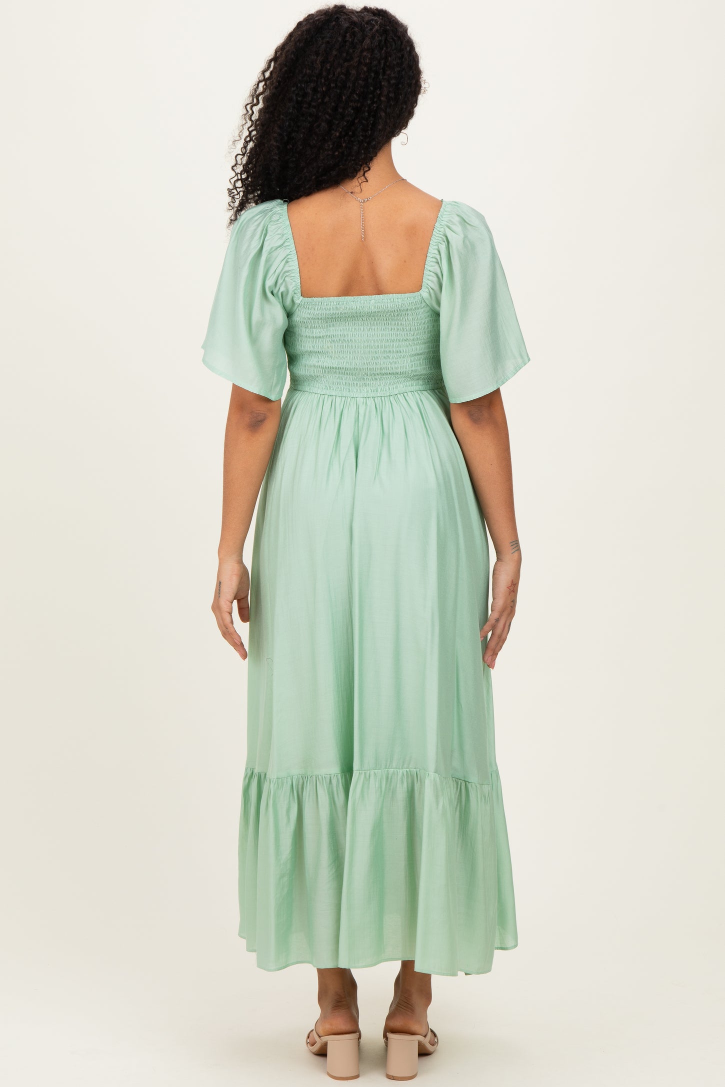 woman wearing a mint green smocked back maxi dress with short puff sleeves and a tiered hem