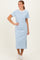 woman wearing a light blue and white striped short sleeve midi dress with a side slit and white sneakers