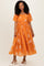 woman wearing an orange floral maxi dress with puff sleeves and a tiered skirt