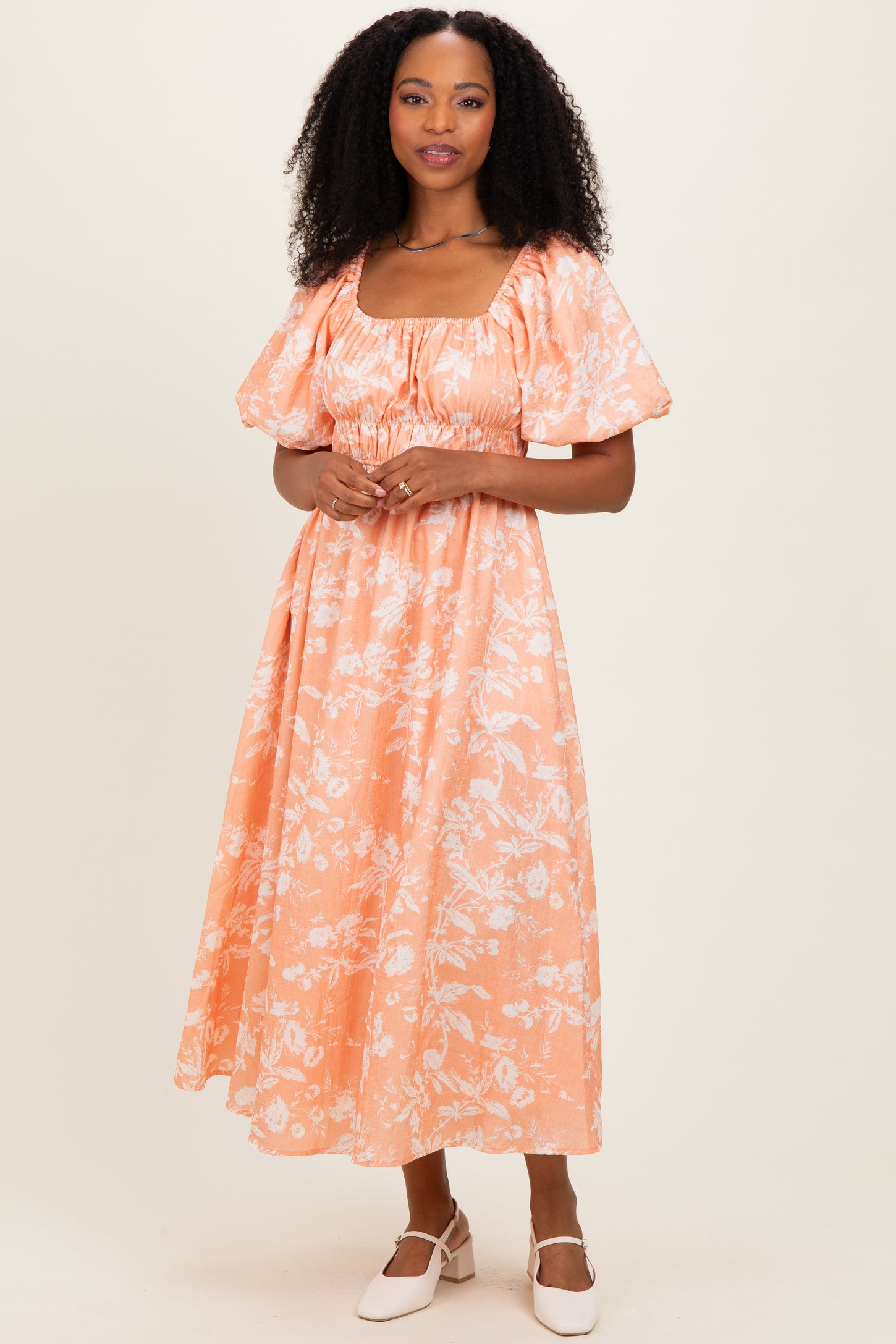 woman wearing an orange floral maxi dress with puff sleeves and a square neckline