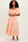 woman wearing an orange floral maxi dress with puff sleeves and a square neckline