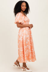 woman wearing a floral orange midi dress with puff sleeves and a smocked bodice