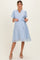 woman wearing a light blue short sleeve maternity dress with buttons and a tie waist, featuring floral embroidery
