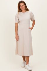 woman wearing a light beige midi dress with puff sleeves and side pockets, paired with white sneakers