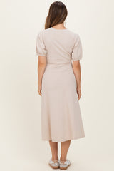 woman wearing a light beige puff sleeve maternity dress, view from the back, with a flowy midi length