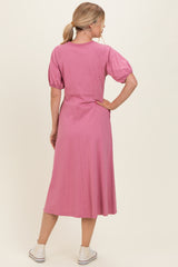 woman wearing a pink midi dress with puff sleeves and a fitted waist, seen from the back