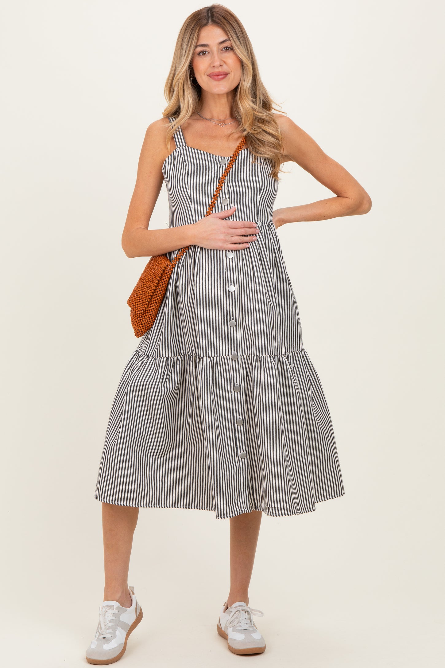 woman wearing a black and white striped maternity dress with a tiered skirt and holding her baby bump