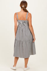 woman wearing a striped midi dress with spaghetti straps and a tiered skirt, viewed from the back
