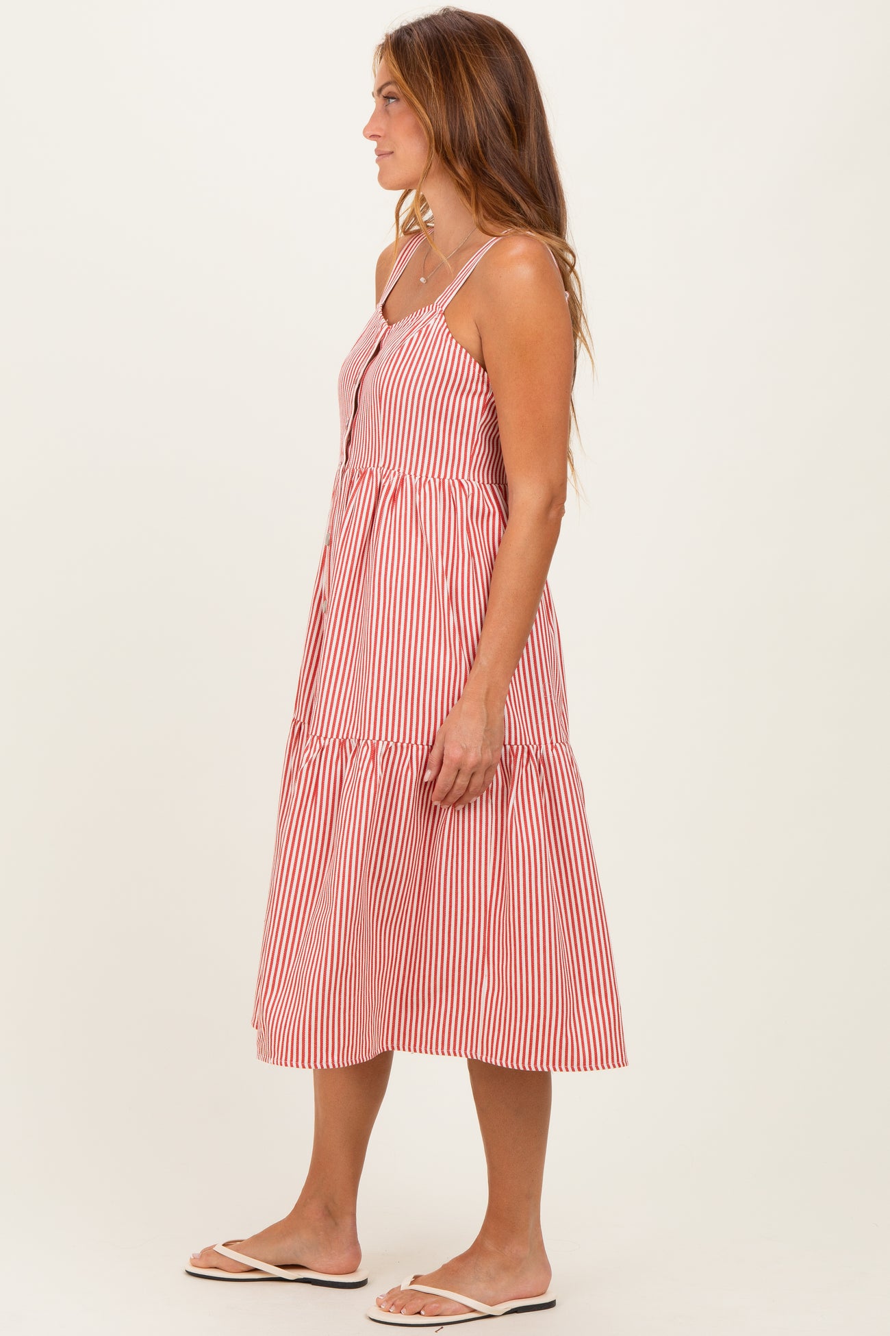 woman wearing a red and white striped midi dress with spaghetti straps and a tiered ruffle hem