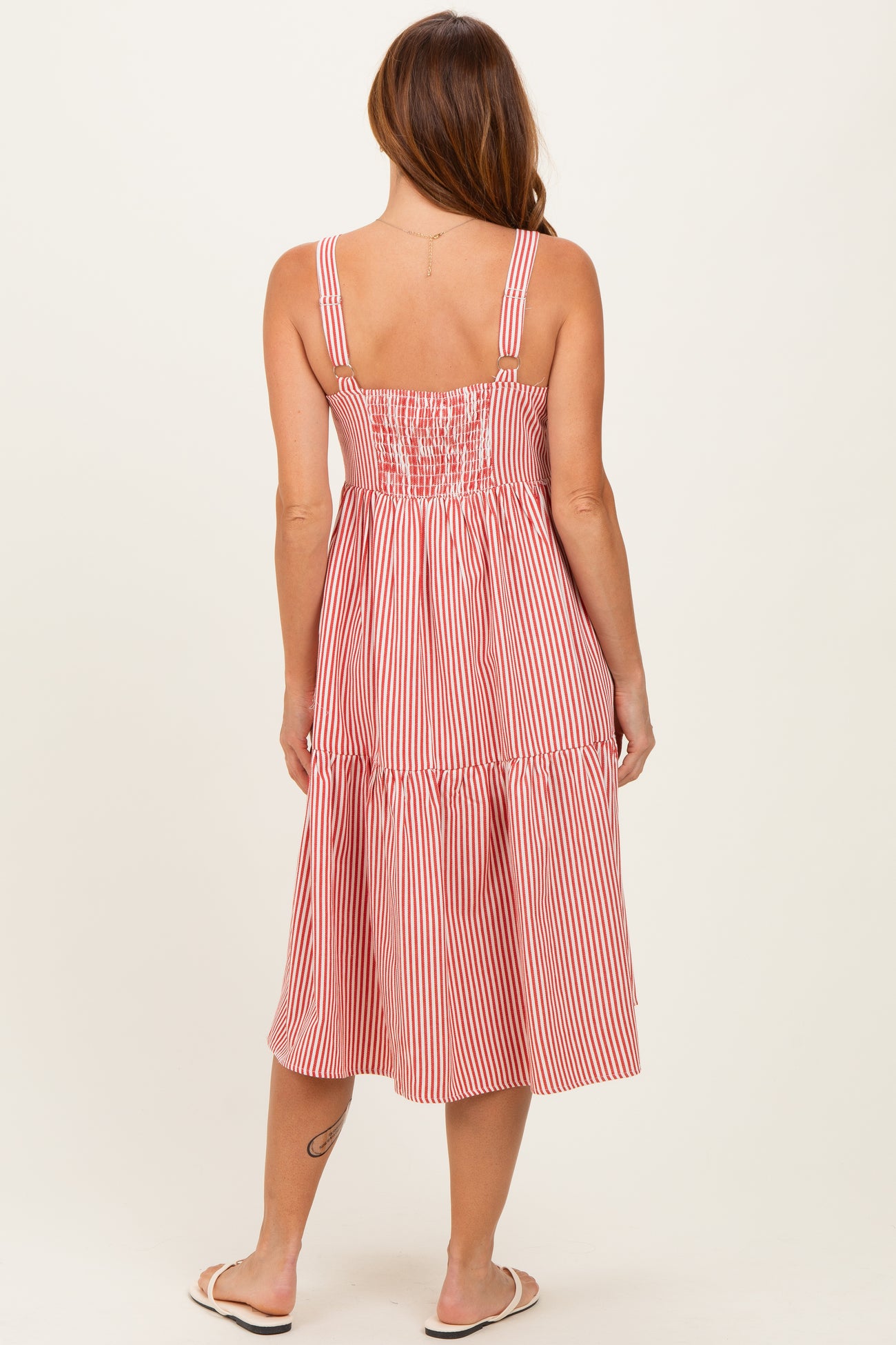 woman wearing a red and white striped midi dress with a smocked back and adjustable straps