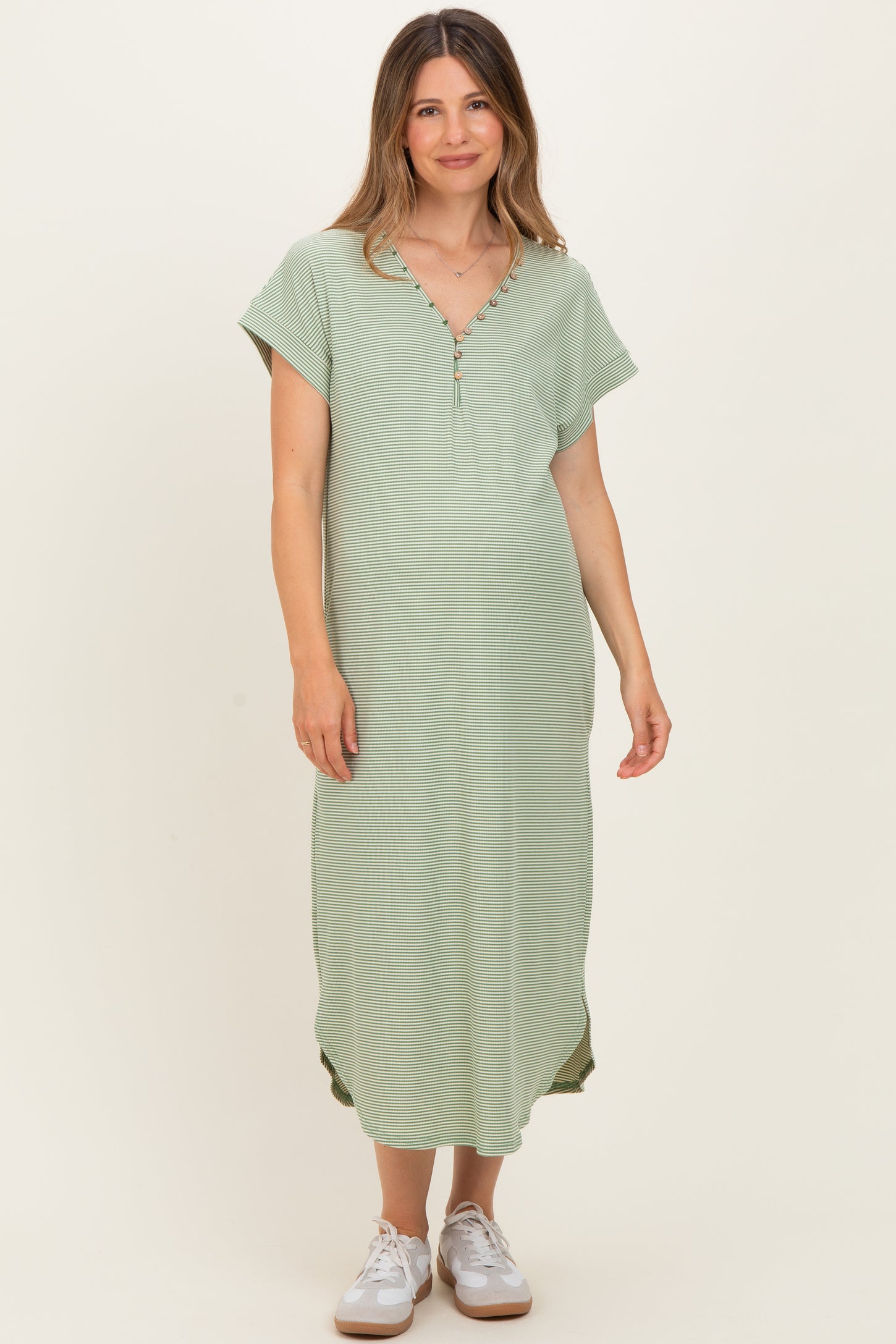 woman wearing a green maternity maxi dress with short sleeves and buttons at the neckline, showing a baby bump
