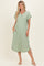 woman wearing a light green short sleeve maxi dress with buttons and side pockets