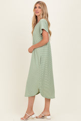 woman wearing a light green short sleeve midi dress with side slits and a relaxed fit