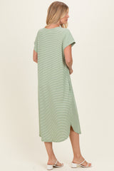 woman wearing a green maxi dress with short sleeves and side slits, standing with her back to the camera