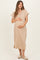 woman wearing a beige short sleeve maternity dress with button details, holding her baby bump