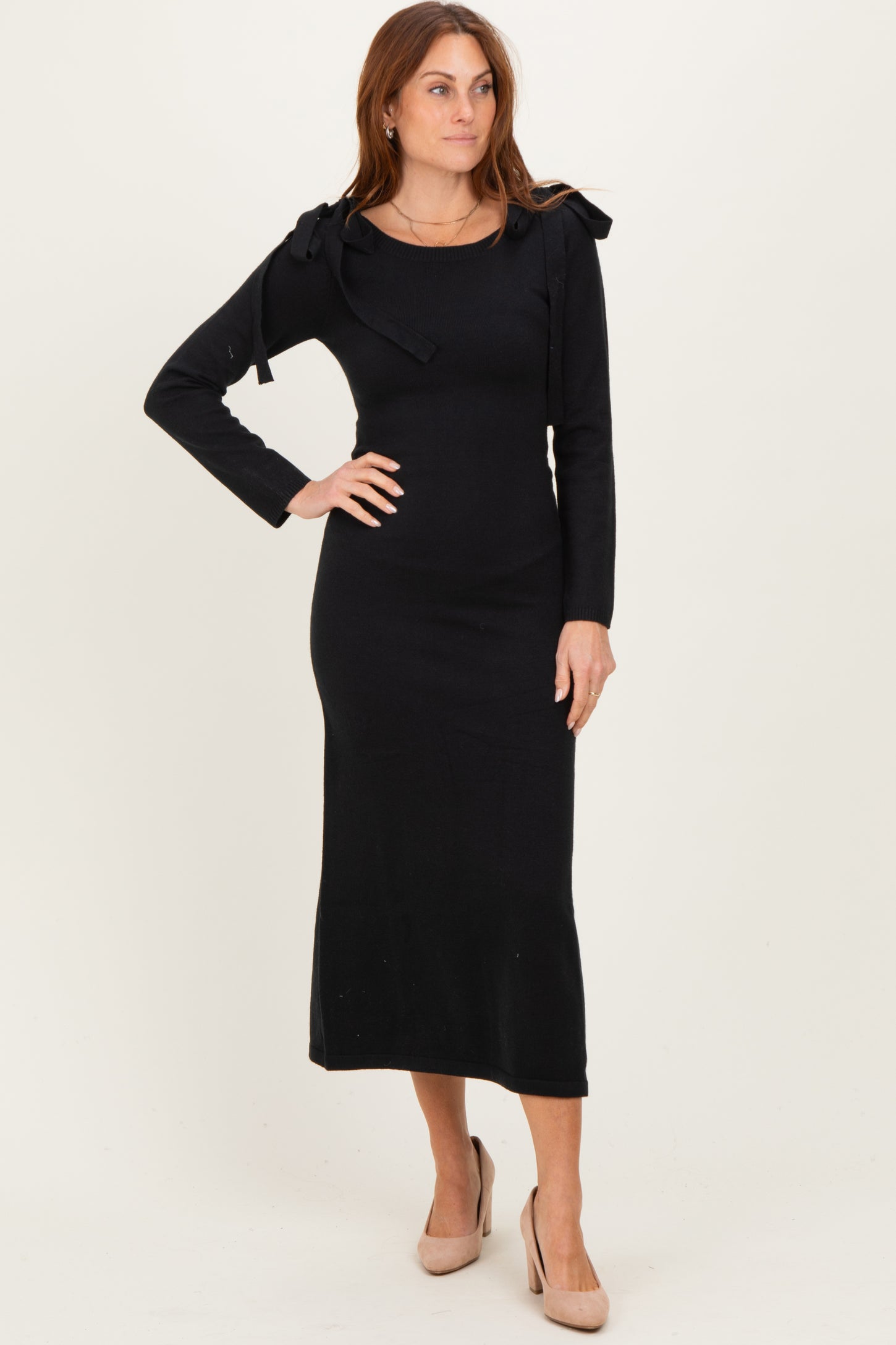 woman wearing a black long sleeve midi dress with tie shoulder details and fitted silhouette