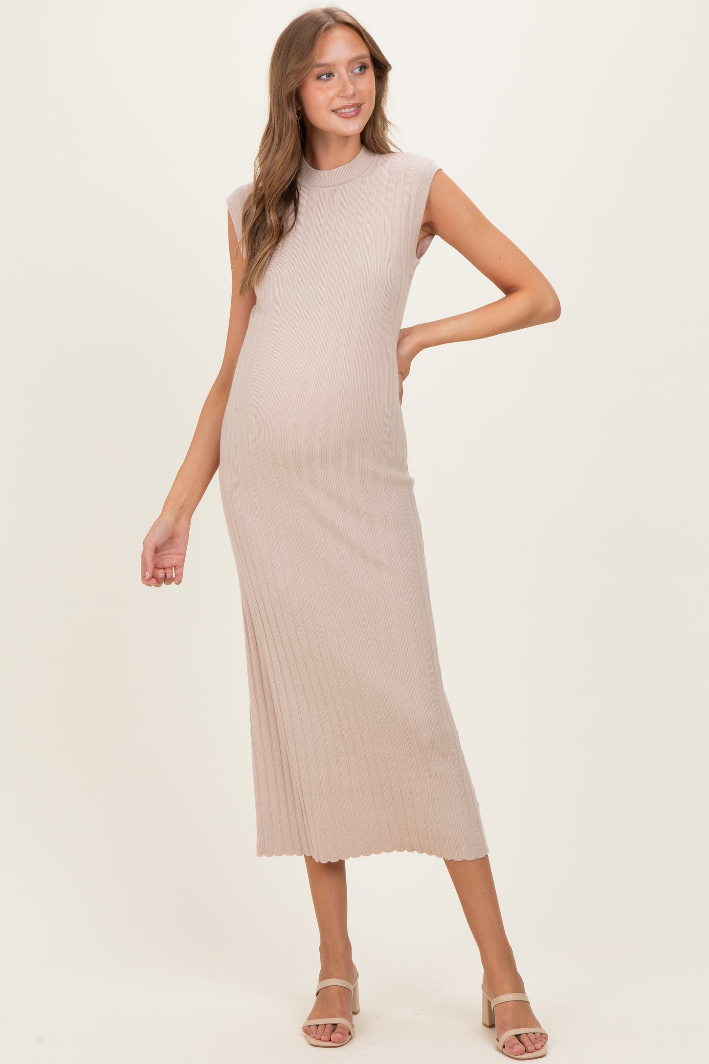 woman wearing a light beige ribbed maternity dress accentuating her baby bump
