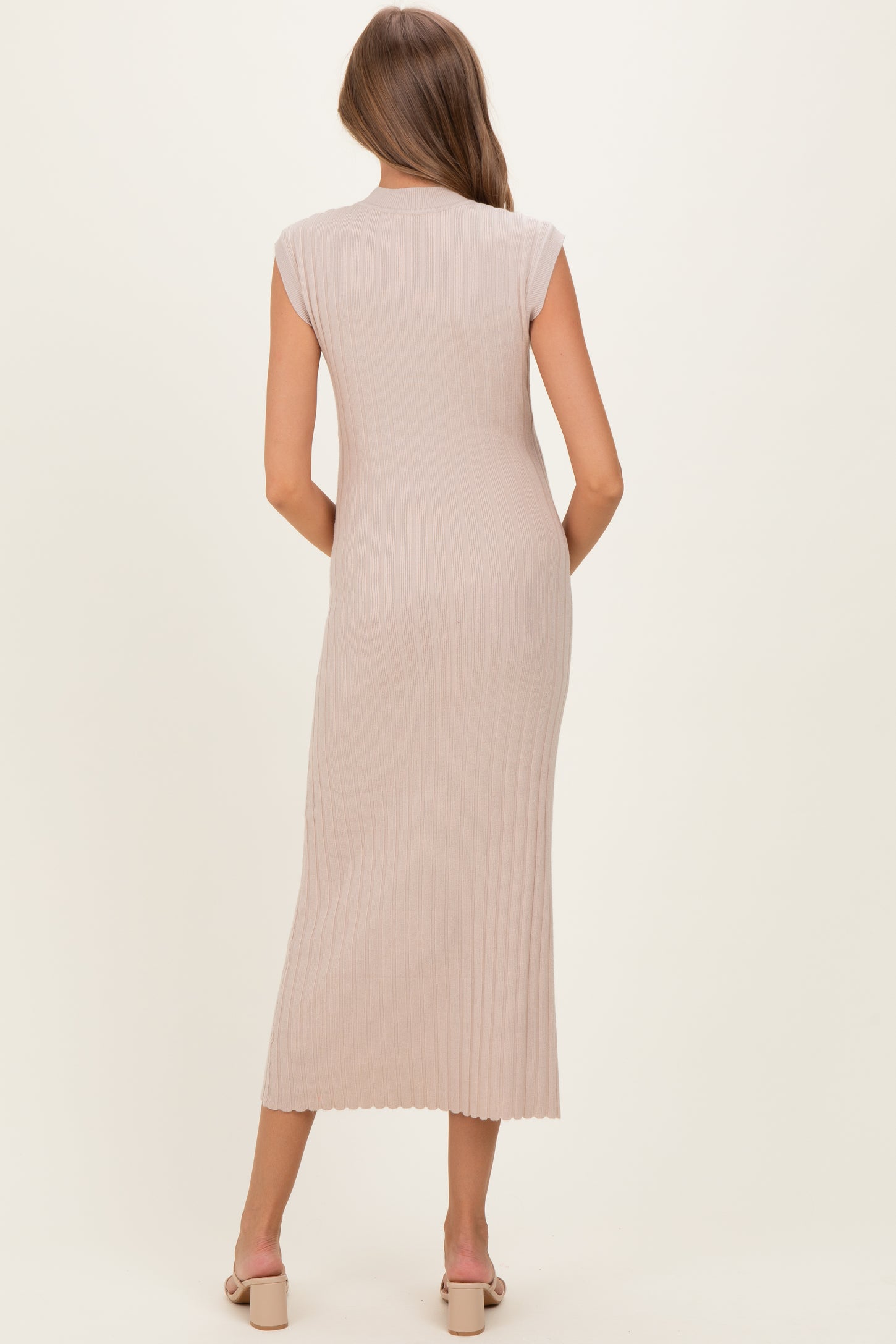 woman wearing a fitted beige sleeveless maternity dress with ribbed texture, shown from the back
