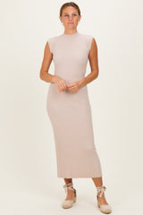 woman wearing a light pink ribbed midi dress with a high neck and cap sleeves, standing and smiling