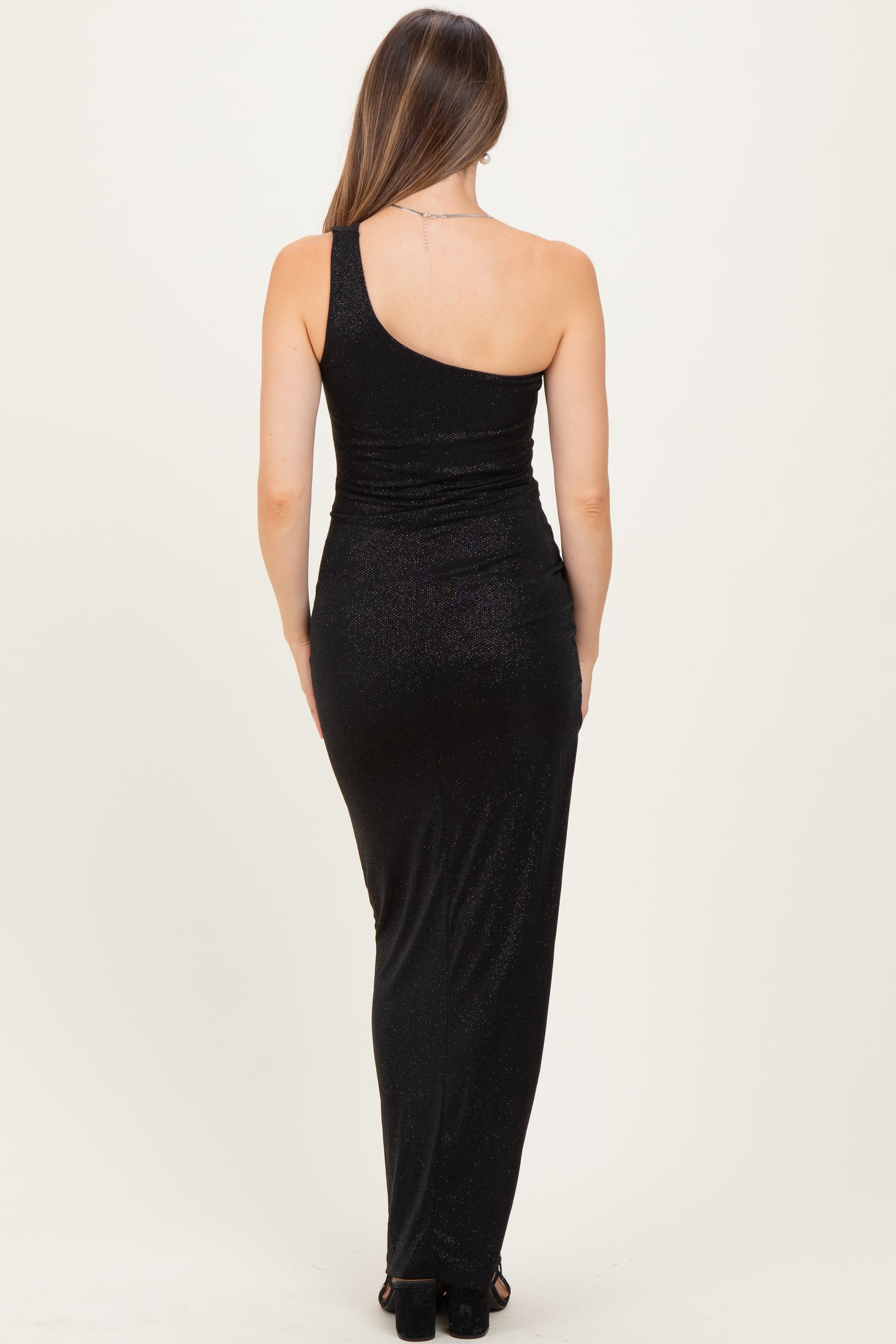 woman wearing a black one-shoulder maternity gown with a fitted silhouette and a floor-length design
