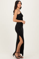 woman wearing a black sparkly maxi dress with a thigh-high slit and side cutout, styled with black strappy heels