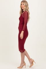 woman wearing a burgundy midi dress with sheer long sleeves and polka dot detailing, styled with nude heels