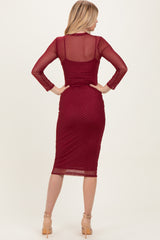 woman wearing a burgundy long sleeve fitted dress with a dotted pattern and a midi length