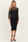 woman wearing a black maternity dress with long sheer sleeves and polka dot design, showing her baby bump