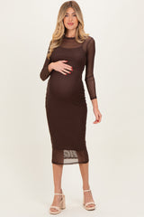 woman wearing a brown polka dot maternity dress with long sleeves and a fitted silhouette, showing her baby bump