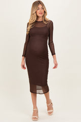 woman wearing a brown polka dot maternity dress with long sleeves and a fitted silhouette, showcasing her baby bump