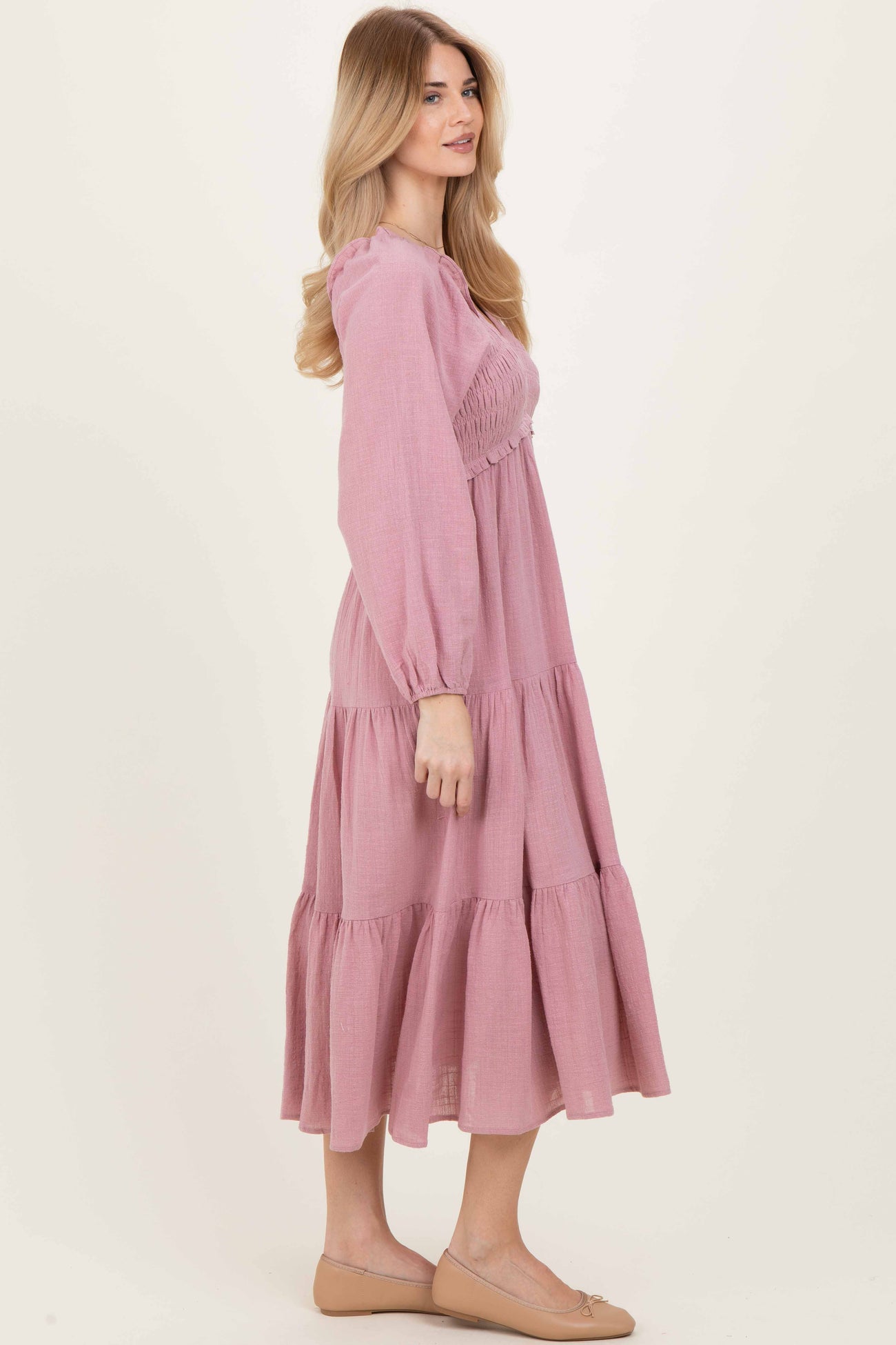 woman wearing a pink tiered maxi dress with long sleeves and smocked bodice