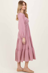 woman wearing a pink tiered maxi dress with long sleeves and smocked bodice