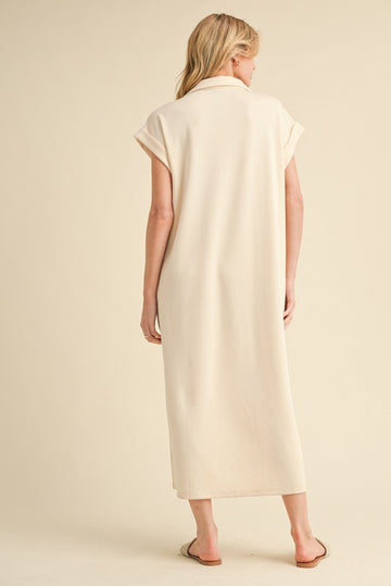 woman wearing a light beige sleeveless maxi dress with a collar, viewed from the back