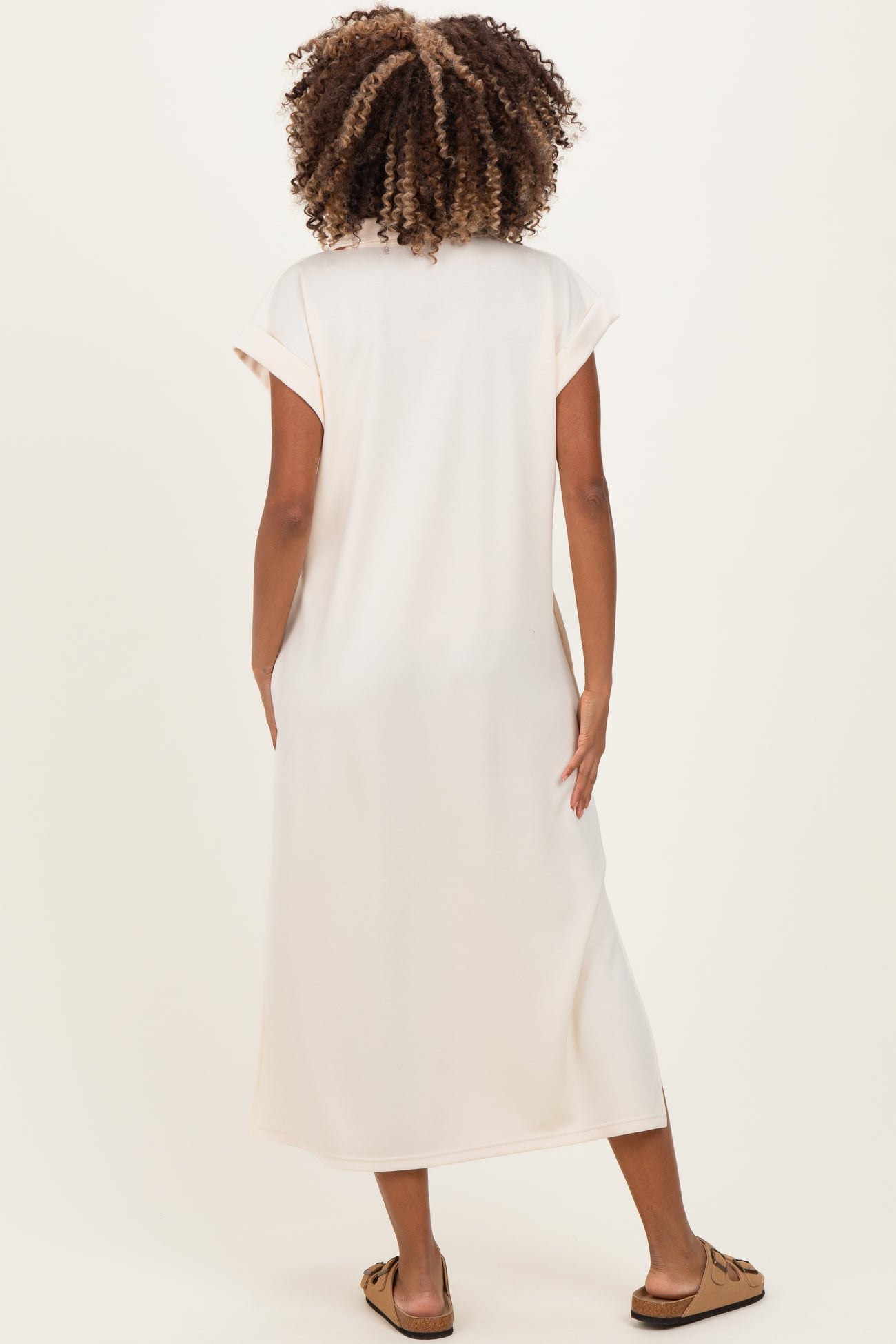 woman wearing a long blush pink maternity dress with short sleeves, seen from the back