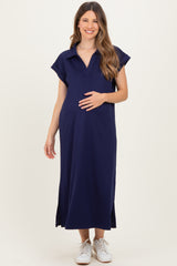 woman wearing a navy blue maternity dress with a polo collar and side slits, holding her baby bump