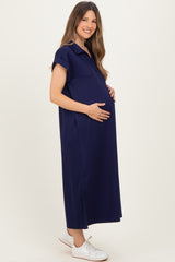woman wearing a navy blue maternity dress with short sleeves and a side slit, holding her baby bump