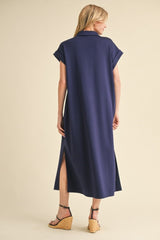 woman wearing a navy blue casual maxi dress with short sleeves and side slits, viewed from the back